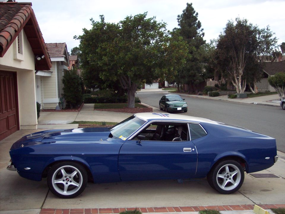 Blue 1971-73 Ford Mustang fastback in profile with white roof and five-spoke wheels