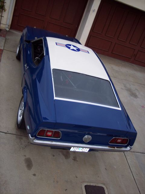 1971 Ford Mustang - A blue 1971 Ford Mustang with a white roof and an air force star decal is parked in front of a garage.