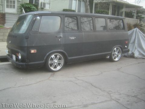 1968 Ford Mustang - A black panel van with aftermarket wheels is parked on a residential street.