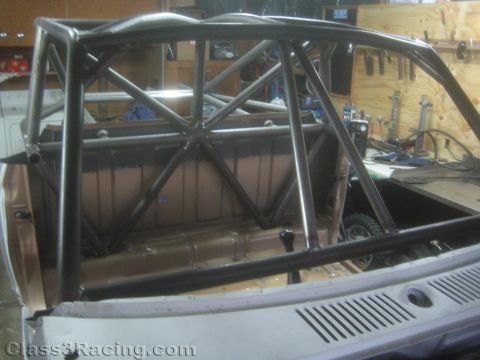 1990 Ford Bronco - Black-painted fabricated roll cage tubing forms a triangulated structure over the rear bed area of a partially built vehicle in a shop.