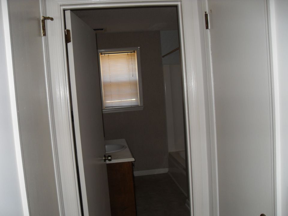 View into a bathroom with a sink and vanity, a window with blinds, and a bathtub
