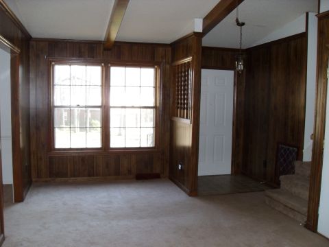 1988 Ford Bronco - A room with wood paneling and carpet features two windows and a doorway leading to stairs.