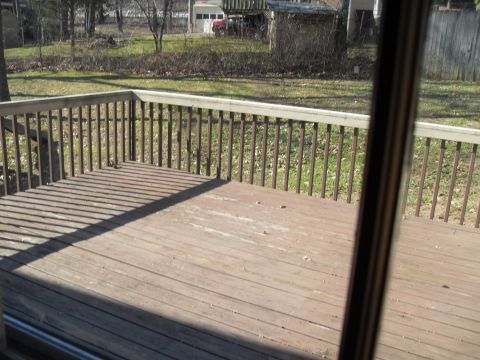 1988 Ford Bronco - View from a wooden deck overlooking a backyard with a red vehicle parked near a garage.