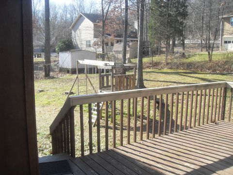1988 Ford Bronco - View of a backyard with a deck, swing set, and shed, taken on a sunny day.