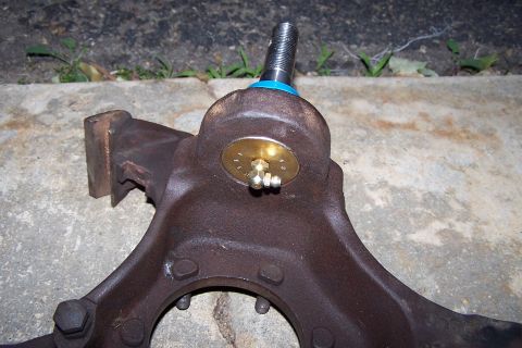 1990 Ford Bronco - This is a close-up view of a vehicle's ball joint assembly, showing its rusty metal components and a brass grease fitting.