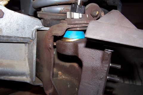 1990 Ford Bronco - Close-up view of a vehicle's ball joint assembly, showing the connection points and a blue bushing.