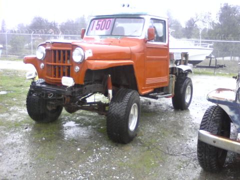 1989 Ford Bronco - Modified orange pickup truck with a "1500" sign in the windshield sits outside.