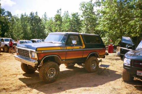 1979 Ford Bronco - This lifted 1979 Ford Bronco features a distinctive two-tone paint scheme with orange, blue, and a yellow stripe.