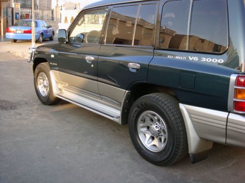 2000 Mitsubishi Montero - This Mitsubishi Pajero features a two-tone paint scheme and side steps, with another car visible in the background.