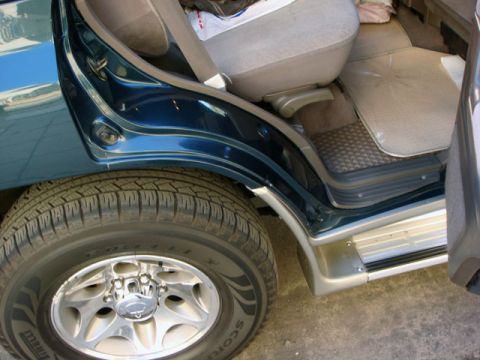 2000 Mitsubishi Montero - Interior shot of a dark blue SUV, focusing on the rear door and seating area.