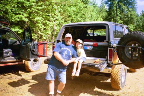 1979 Ford Bronco - A man and child pose by the open tailgate of a gray Ford Bronco, with another vehicle to the left.
