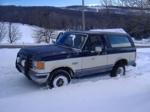 1988 Ford Bronco - This two-tone Ford Bronco is partially buried in snow, with its front tires deep in the drift.