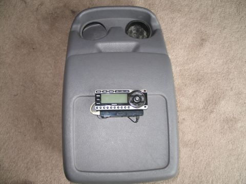 1995 Ford Bronco - Aftermarket stereo unit mounted on a gray vehicle center console with cup holders.