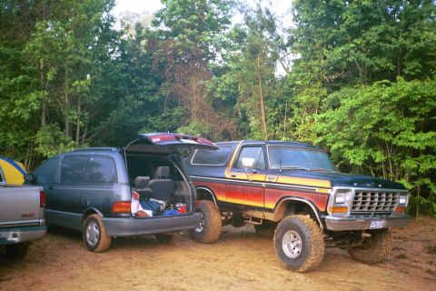 1979 Ford Bronco - Ford Bronco and minivan parked outdoors with trees in the background. The Bronco appears to be a 1978 model.