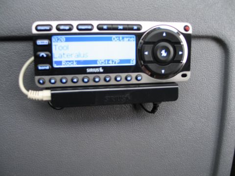 1995 Ford Bronco - Close-up of a SiriusXM radio unit mounted in a vehicle's interior, showing song information.
