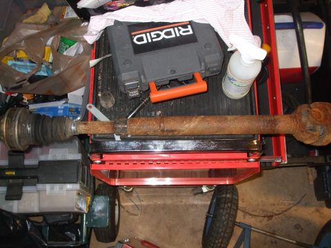 1996 Jeep Grand Cherokee - A rusty driveshaft rests on a red cart, surrounded by tools and supplies.
