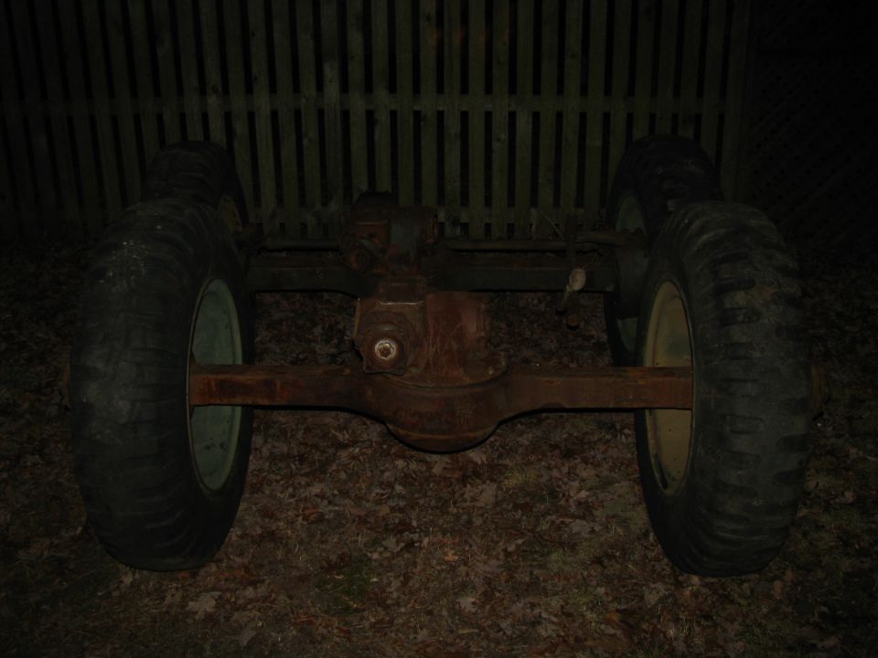 Rear axle assembly with two large tires and rusty metal components, viewed from the rear