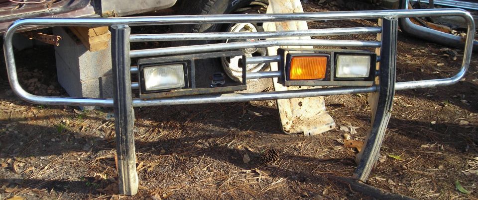Removed chrome brush guard with headlights and amber turn signal standing on dirt