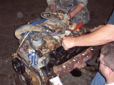 1978 Ford Bronco - A V8 engine is being worked on by several people, with a can of beer resting on the engine block.