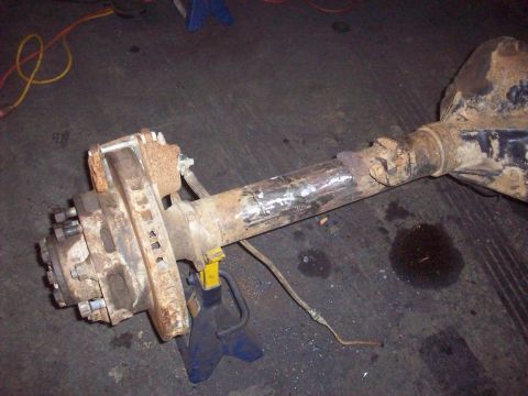 1978 Ford Bronco - A heavily used axle assembly, likely from an older truck or SUV, rests on blue jack stands in a workshop.