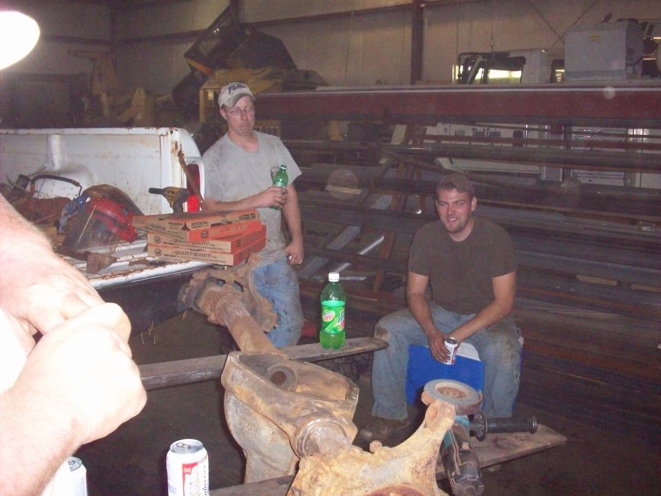 Truck bed with pizza boxes and a welding mask, two men in workshop