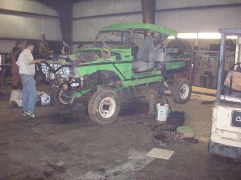 1978 Ford Bronco - A heavily modified 1978 Ford Bronco is undergoing repairs inside a garage, showing its lifted suspension and custom exterior.