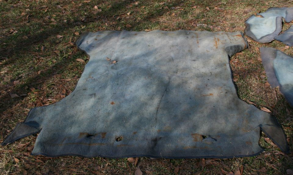 Several pieces of blue carpet laid out on grass and dirt