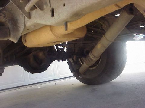 1989 Ford Bronco - The rear axle, driveshaft, and exhaust components are visible from underneath the vehicle.