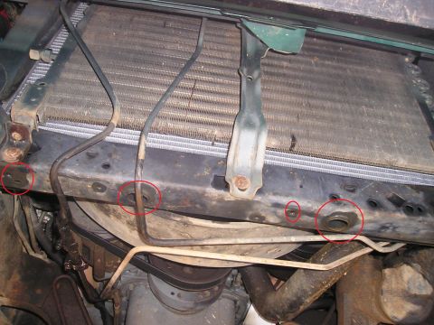 1989 Ford Bronco - Close-up view of the front of a vehicle's engine bay, focusing on the radiator and surrounding support structure. Several metal tubes and h…