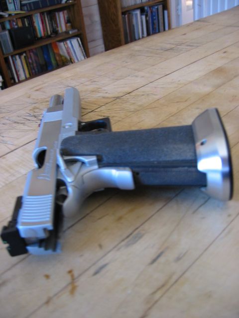 1996 Ford Bronco - A handgun with a textured grip is resting on a wooden table. In the background, bookshelves are filled with books.