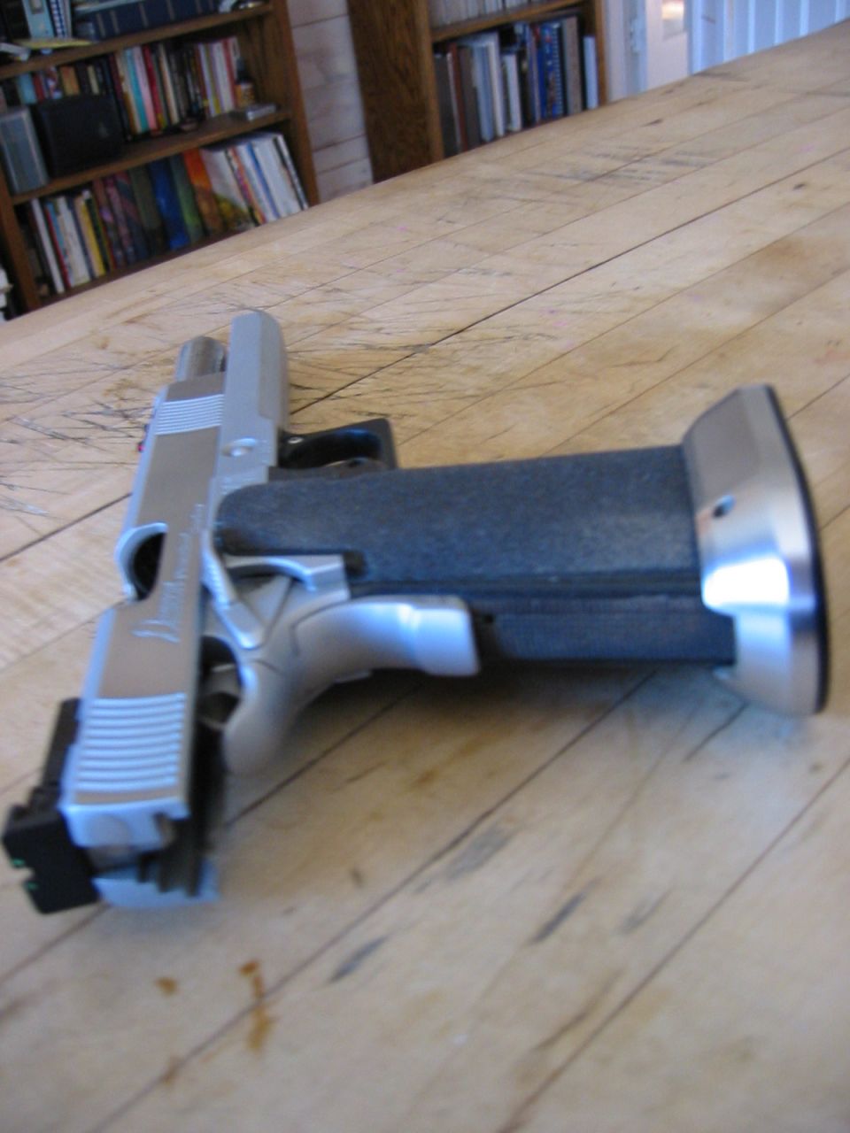Handgun on a wooden table with bookshelves in the background.