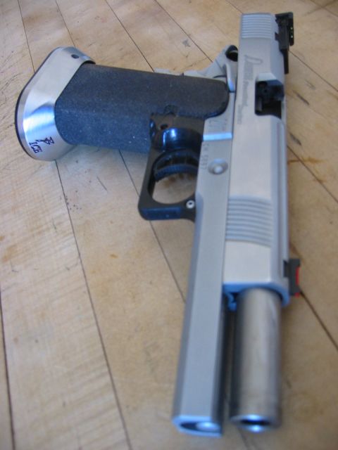 1996 Ford Bronco - A silver semi-automatic pistol with a black grip rests on a wooden floor. The pistol has a silver frame and barrel, with a textured black g…