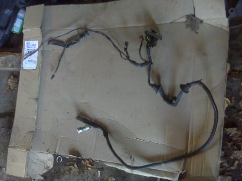 1995 Ford Bronco - A removed wiring harness laid out flat on a flattened cardboard box, showing black loom-wrapped branches, several plastic connectors, a rou…