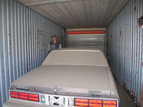 1991 Ford LTD Crown Victoria - Photograph of a dust-covered Chevrolet Caprice stored in a shipping container, not a technical document.