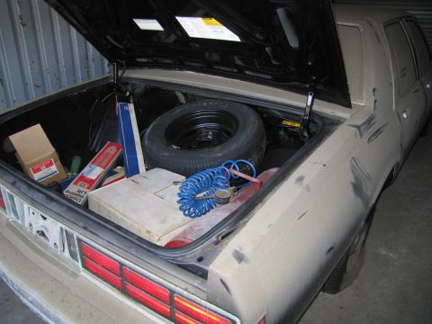 1991 Ford LTD Crown Victoria - Photograph of an open vehicle trunk loaded with a spare and parts boxes, not a technical document.