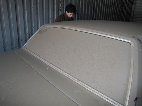1991 Ford LTD Crown Victoria - Photograph of the dusty rear roofline of a stored car with a person behind it, not a technical document.