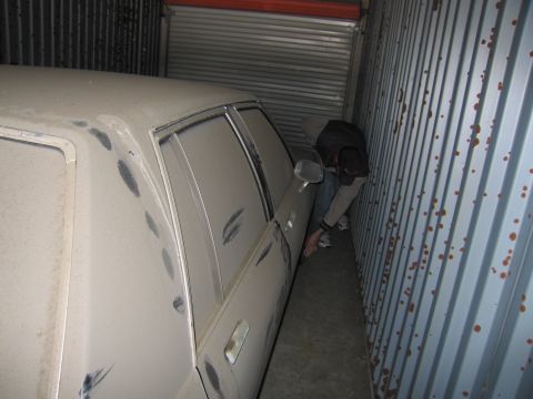 1991 Ford LTD Crown Victoria - Photograph of a car squeezed into a storage container with a person beside it, not a technical document.