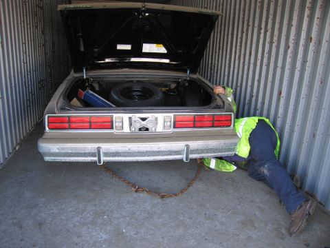 1991 Ford LTD Crown Victoria - Photo of a gray Chevrolet sedan with its trunk open as a person in a hi-vis vest works behind it in a storage container.