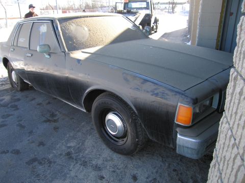 1991 Ford LTD Crown Victoria - Photo of the front three-quarter view of a dusty black Chevrolet sedan outdoors in winter.