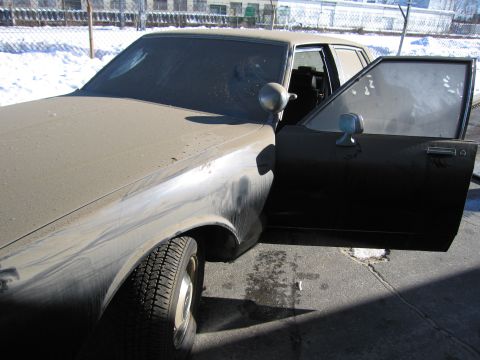 1991 Ford LTD Crown Victoria - Photo of a dust-streaked Chevrolet sedan with the front door open in a snowy industrial lot.