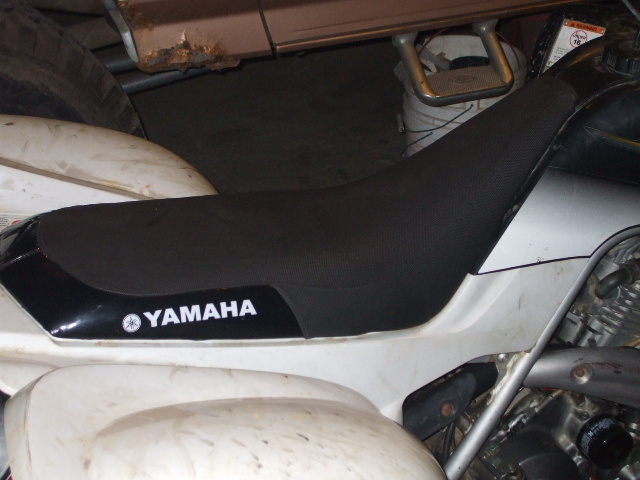 Side view of white Yamaha ATV with black seat and YAMAHA logo on side panel in a garage