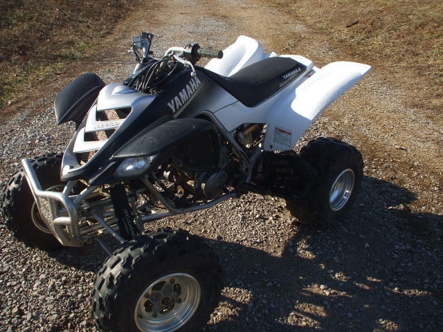 White and black Yamaha Raptor sport ATV quad parked on a gravel road