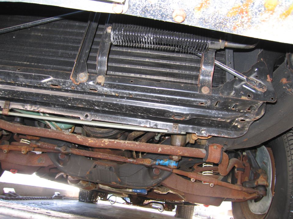 Underside view of a car showing radiator, frame rail and rusty suspension components