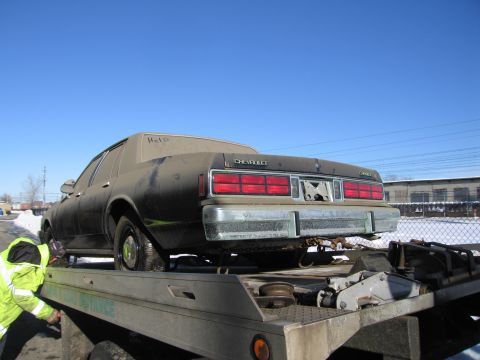 1991 Ford LTD Crown Victoria - Photograph of the rear of a grimy Chevrolet Caprice secured on a flatbed tow truck in winter.