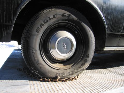 1991 Ford LTD Crown Victoria - Photograph of a Goodyear Eagle GT tire and Chevrolet hubcap secured by a chain on a flatbed bed.