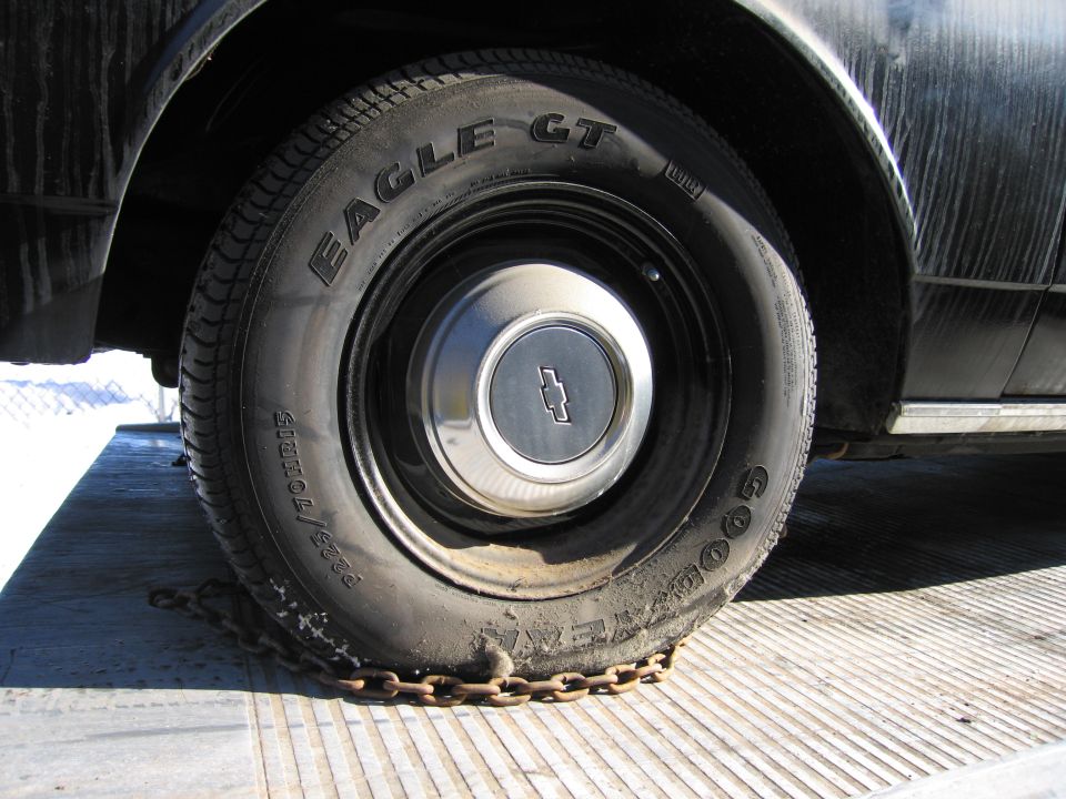 Close-up of a Goodyear Eagle GT tire and Chevrolet hubcap with tie-down chain