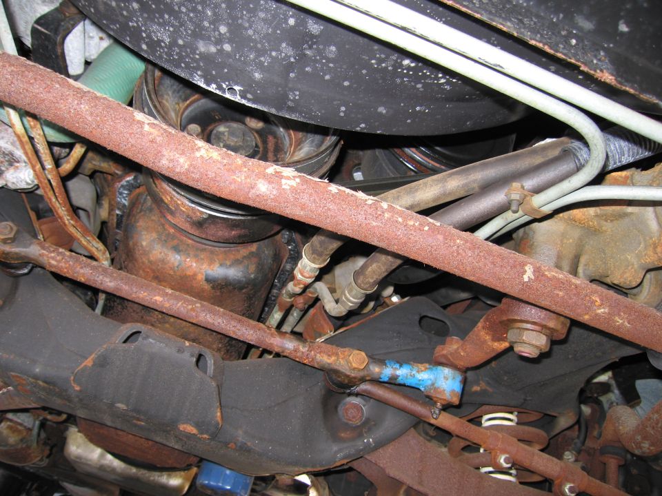 Underside view of a vehicle showing rusty exhaust, sway bar and suspension