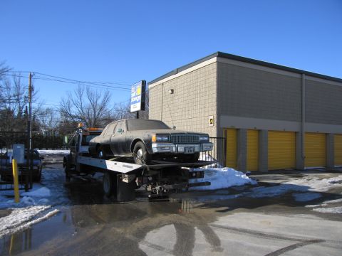 1991 Ford LTD Crown Victoria - Photograph of a sedan being delivered on a flatbed tow truck, not a technical document.