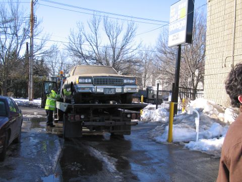 1991 Ford LTD Crown Victoria - Photograph of workers unloading a sedan from a flatbed tow truck, not a technical document.