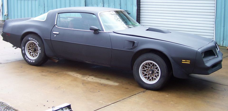 Black Pontiac Firebird with a hood scoop and snowflake wheels
